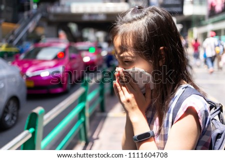 Asian little child girl blowing nose in paper handkerchief,female people sneezing in a tissue in the city street,dirty air,polluted air prevent PM 2.5,bad smell,concept of air pollution,dust allergies