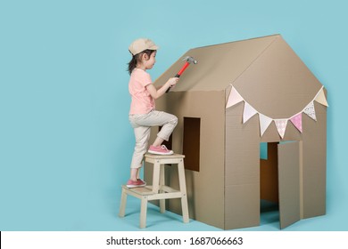 Asian little child girl building her cardboard house isolated on blue long banner with copy space for your text, Creative at home with family concept