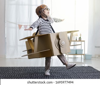 Asian little child girl playing with cardboard toy airplane handicraft isolated in home with copy space for your text, Creative with family and dreaming of flying concept