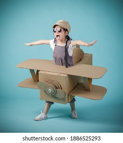 Asian little child girl playing with cardboard toy airplane handicraft isolated on blue background, Creative at home and dreams of flight concept