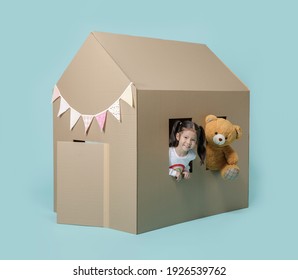 Asian little child girl playing with cardboard house with her teddy bear  isolated on blue long banner, Creative at home with family concept