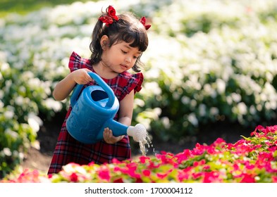 Asian Little Child Girl Is Pouring Water On The Little Tree Plant. Kid Helps The World To Care And Save The Natural Environment. Ecology Concept.