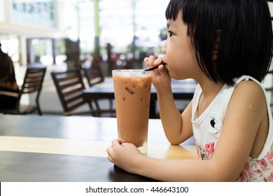 Asian Little Chinese Girl Drinking Ice Milk Tea In Outdoor Cafe