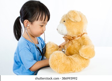 Asian Little Chinese Girl Playing Doctor with Teddy Bear isolated on white background