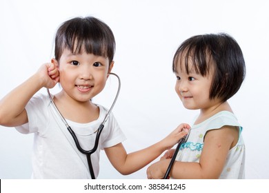 Asian Little Chinese Girls Playing as Doctor and Patient with Stethoscope isolated on white background