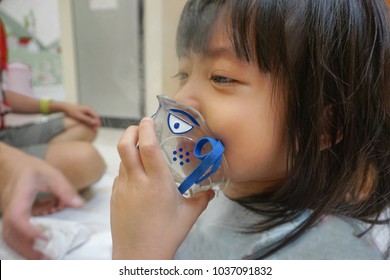 Asian Little Cute Girl With Influenza Hospital Admission. 
Kid Patient Holding  The Mask Of Inhaler, Getting Bronchodilator.
