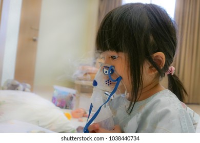 Asian Little Cute Girl With Influenza Hospital Admission. 
Kid Patient Holding  The Mask Of Inhaler, Getting Bronchodilator.
