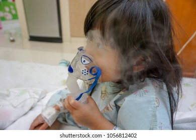 Asian Little Cute Girl With Influenza Hospital Admission. 
Kid Patient Holding  The Mask Of Inhaler, Getting Bronchodilator.
