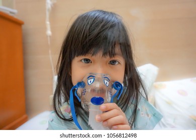 Asian Little Cute Girl With Influenza Hospital Admission. 
Kid Patient Holding  The Mask Of Inhaler, Getting Bronchodilator.
