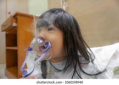 Asian Little Cute Girl With Influenza Hospital Admission. 
Kid Patient Holding  The Mask Of Inhaler, Getting Bronchodilator.