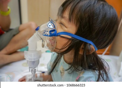 Asian Little Cute Girl With Influenza Hospital Admission. 
Kid Patient Holding  The Mask Of Inhaler, Getting Bronchodilator.
