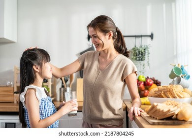 Asian Little Cute Kid Holding A Cup Of Milk And Drinking With Mother. Attractive Mom Teach And Support Young Girl Daughter Take Care Of Her Body, Sipping A Milk After Wake Up For Health Care In House.