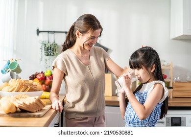 Asian Little Cute Kid Holding A Cup Of Milk And Drinking With Mother. Attractive Mom Teach And Support Young Girl Daughter Take Care Of Her Body, Sipping A Milk After Wake Up For Health Care In House.