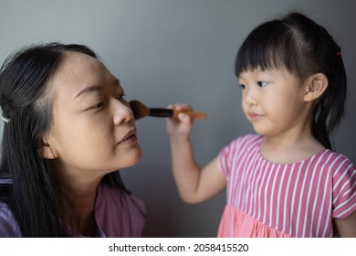 Asian Little Daughter Doing Make Up Her Mom. Concept Of Love And Connection Of Mother And Kid.