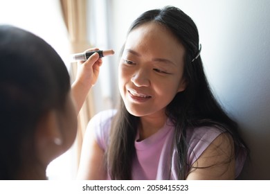 Asian Little Daughter Doing Make Up Her Mom. Concept Of Love And Connection Of Mother And Kid.