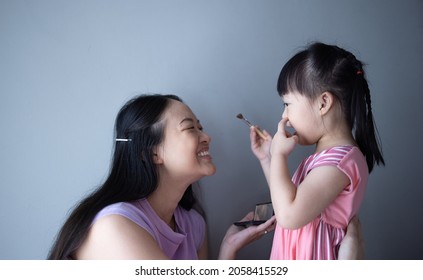 Asian Little Daughter Doing Make Up Her Mom. Concept Of Love And Connection Of Mother And Kid.