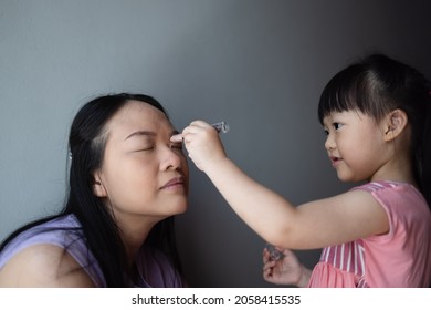 Asian Little Daughter Doing Make Up Her Mom. Concept Of Love And Connection Of Mother And Kid.