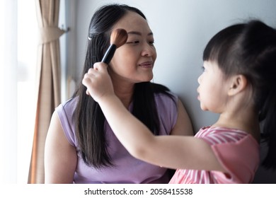 Asian Little Daughter Doing Make Up Her Mom. Concept Of Love And Connection Of Mother And Kid.