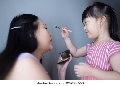 Asian Little Daughter Doing Make Up Her Mom. Concept Of Love And Connection Of Mother And Kid.