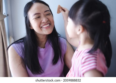 Asian Little Daughter Doing Make Up Her Mom. Concept Of Love And Connection Of Mother And Kid.