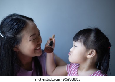 Asian Little Daughter Doing Make Up Her Mom. Concept Of Love And Connection Of Mother And Kid.