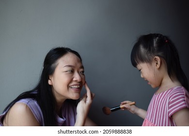 Asian Little Daughter Doing Make Up Her Mom. Concept Of Love And Connection Of Mother And Kid.