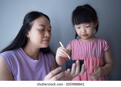 Asian Little Daughter Doing Make Up Her Mom. Concept Of Love And Connection Of Mother And Kid.