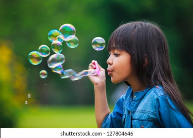 Asian little girl is blowing a soap bubbles, Outdoor Portrait