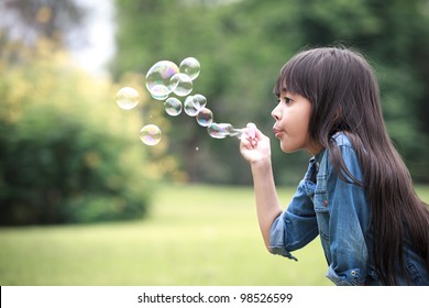 Asian little girl is blowing a soap bubbles