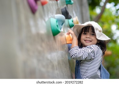 Asian little girl climbing a rock wall