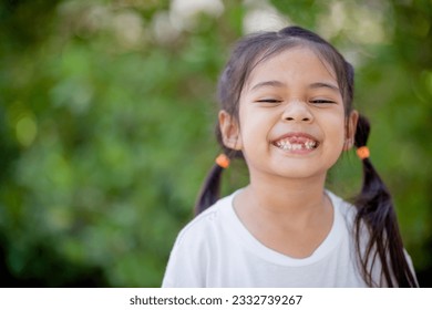 Asian little girl displays a missing tooth. - Powered by Shutterstock