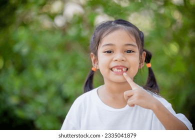 Asian little girl displays a missing tooth. - Powered by Shutterstock