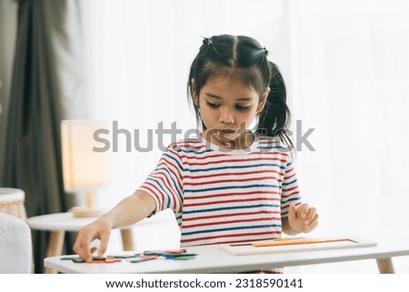 Asian little girl drawing with crayons in the living room at home