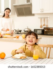 Asian Little Girl Eating Bread While Drinking Juice