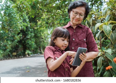 Asian Little Girl Enjoy Watching A Video Using Cell Phone With Her Grandma