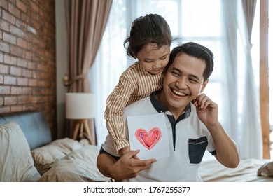 Asian little girl gives her father a heart-drawn paper as a symbol of love when meeting his father - Shutterstock ID 1767255377