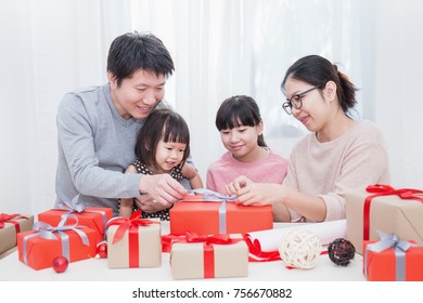 Asian Little Girl Help Her Father And Mother  Wrapping Gift Box, Celebration Holiday Christmas Mother's Day Concept. Happy Asian Family Unwrap Gift Boxed Together.