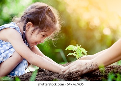 Asian little girl   parent planting young tree black soil together as save world concept in vintage color tone