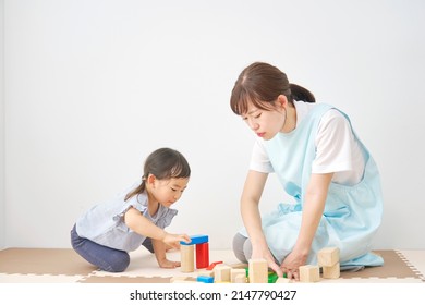 Asian Little Girl Playing With The Building Blocks With The Nursery Teacher