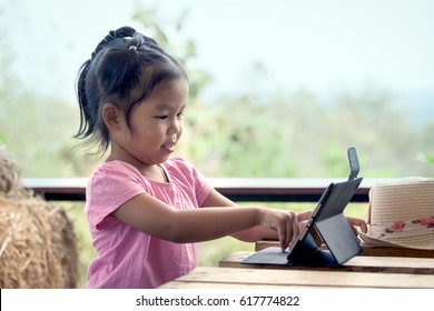 Asian Little Girl Is Playing Ipad Tablet In Vintage Color Tone