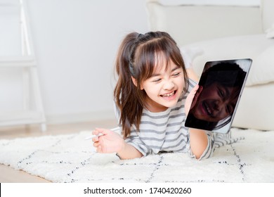 Asian Little Girl Playing Tablet On The Carpet