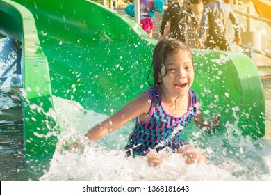 Asian little girl playing water slide in water park on summer holiday