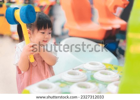 Asian little girl playing whack a mole arcade game at  amusement park, She happy and enjoy, Learning and active of kids concept.