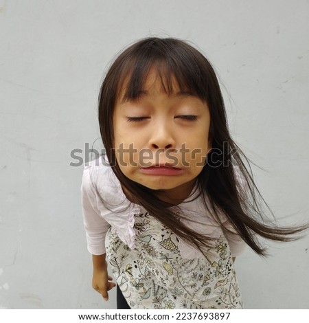 asian little girl pursed mouth and slightly downcast body expression with long black hair with cute bangs