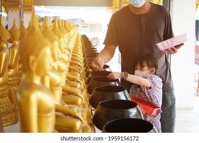 Asian Little Girl Put Mask And Make Merit At The Temple. Buddhist Make Merit, Pay Coins