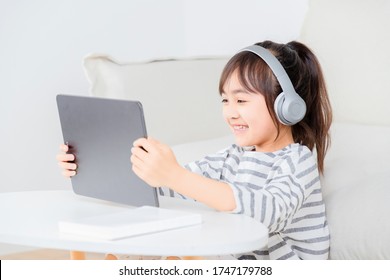 Asian little girl sitting online on the carpet - Powered by Shutterstock