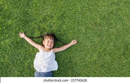 Asian little girl smile and lay on grass