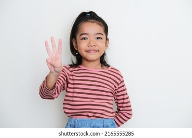 Asian Little Girl Smiling To The Camera And Give Three Fingers Sign