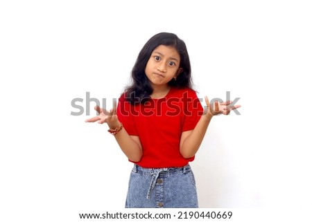 Asian little girl standing with confused expression with open arms, no idea and doubtful face