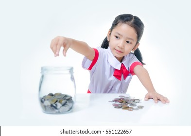 Asian Little Girl In Thai Student Uniform Putting Coin To Glass Jar, Focus On Face Shallow Depth Of Field